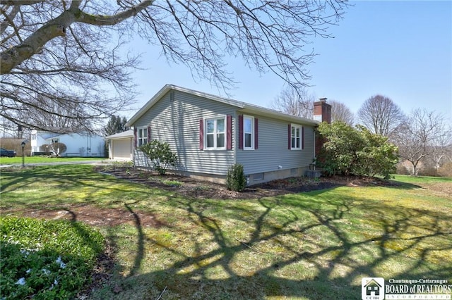 view of side of property featuring a lawn, a chimney, and a detached garage
