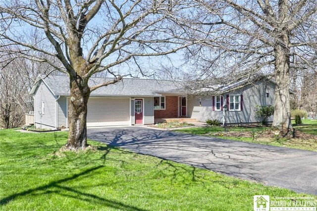 ranch-style house with an attached garage, aphalt driveway, and a front yard