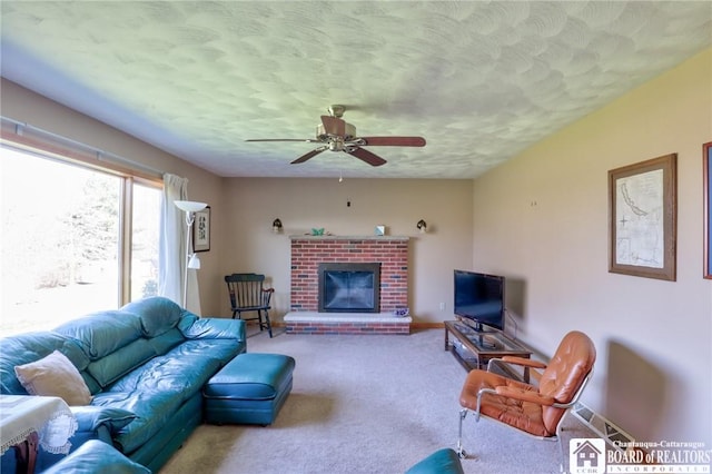 living area with carpet flooring, a textured ceiling, baseboards, a ceiling fan, and a fireplace