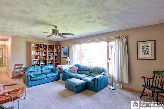 living area with baseboards, visible vents, carpet, and ceiling fan