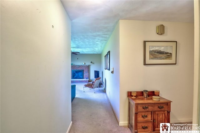hallway featuring baseboards, a textured ceiling, and light carpet