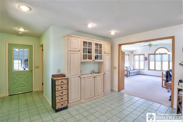 kitchen featuring ceiling fan, light carpet, baseboards, and light countertops