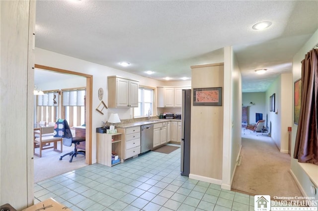kitchen with stainless steel appliances, light countertops, a sink, a textured ceiling, and light colored carpet