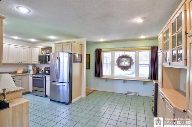 kitchen featuring a textured ceiling, visible vents, baseboards, light countertops, and appliances with stainless steel finishes