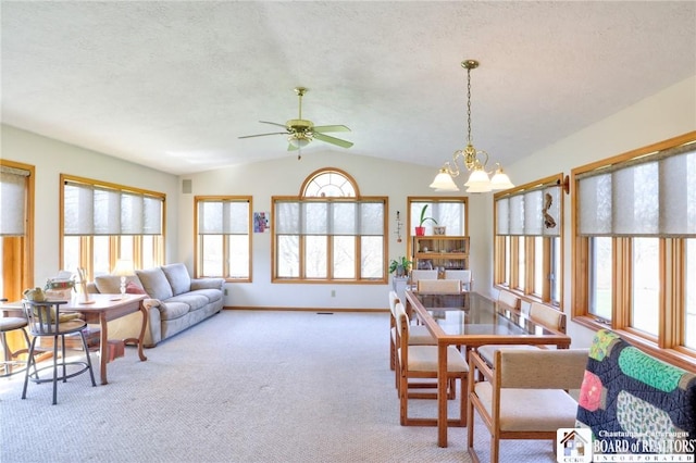 dining area with vaulted ceiling, ceiling fan with notable chandelier, carpet floors, and a wealth of natural light