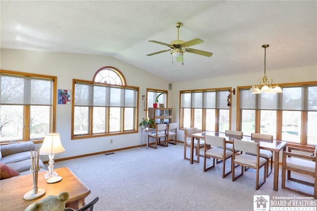 dining room featuring baseboards, visible vents, light colored carpet, lofted ceiling, and ceiling fan with notable chandelier