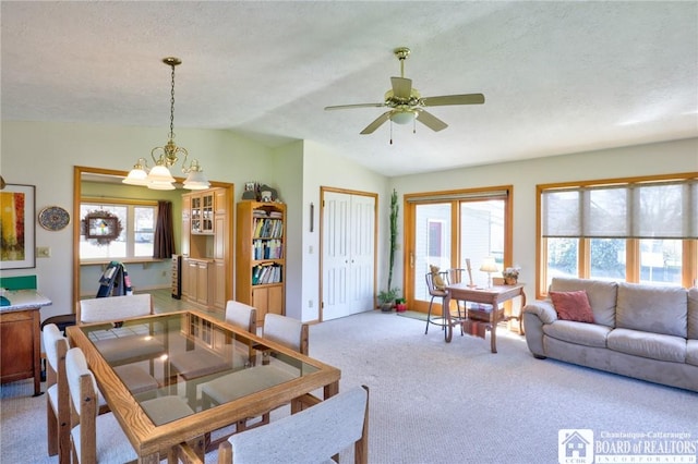 dining area featuring a wealth of natural light, vaulted ceiling, ceiling fan with notable chandelier, and carpet