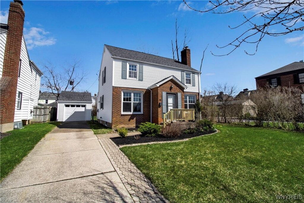 view of front of home with a chimney, a front lawn, driveway, an outbuilding, and brick siding