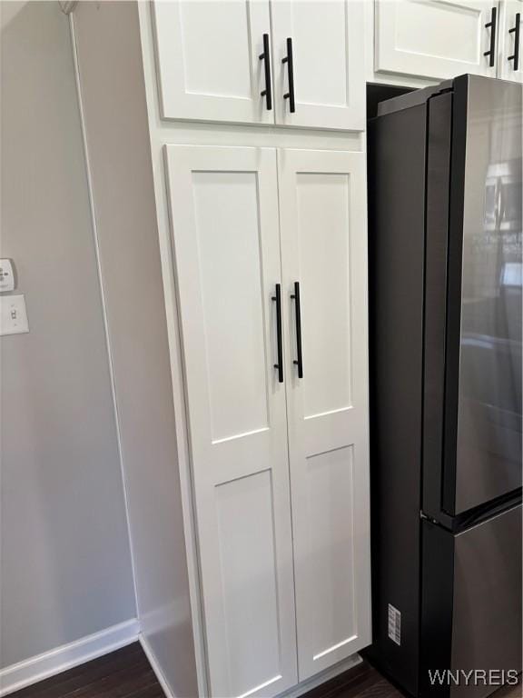 details featuring white cabinets, freestanding refrigerator, baseboards, and dark wood-style flooring