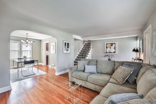 35 University Ct, Amherst, NY 14226 - living area with arched walkways, light wood-style floors, baseboards, a chandelier, and stairs