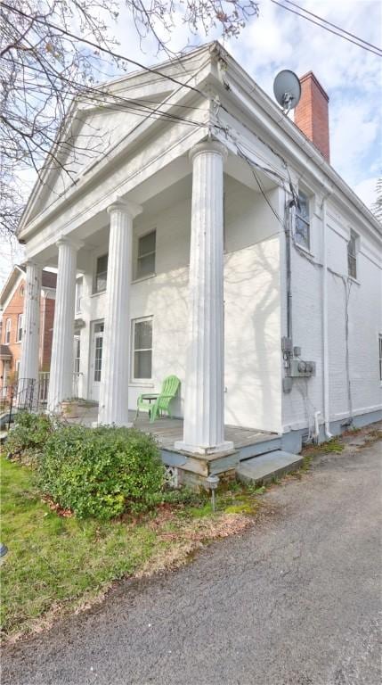 view of side of home with a chimney and a porch