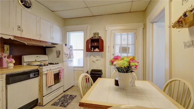 kitchen with tile counters, white appliances, light tile patterned floors, white cabinets, and a paneled ceiling
