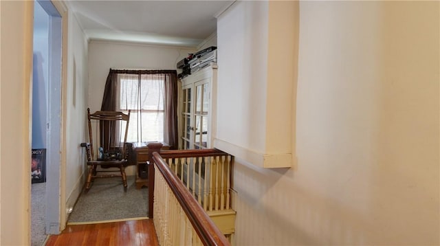 corridor featuring wood finished floors, an upstairs landing, and ornamental molding