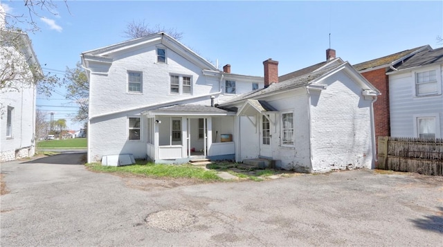 view of front of property featuring fence, a chimney, and brick siding