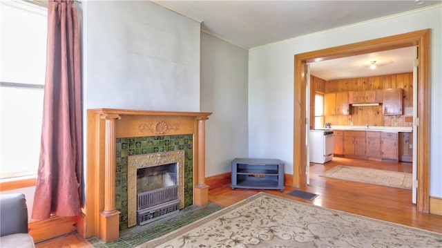 living area featuring crown molding, wood finished floors, and a tiled fireplace