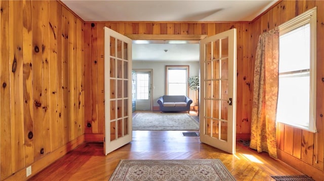 entryway featuring wood finished floors, french doors, wood walls, and visible vents