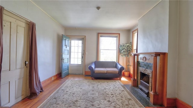 sitting room with light wood-style flooring, baseboards, a fireplace, and crown molding