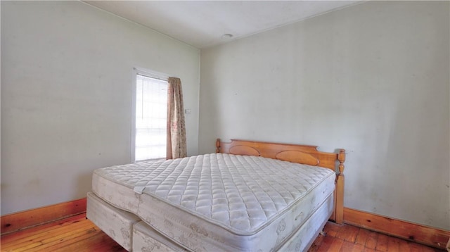 bedroom with wood-type flooring and baseboards