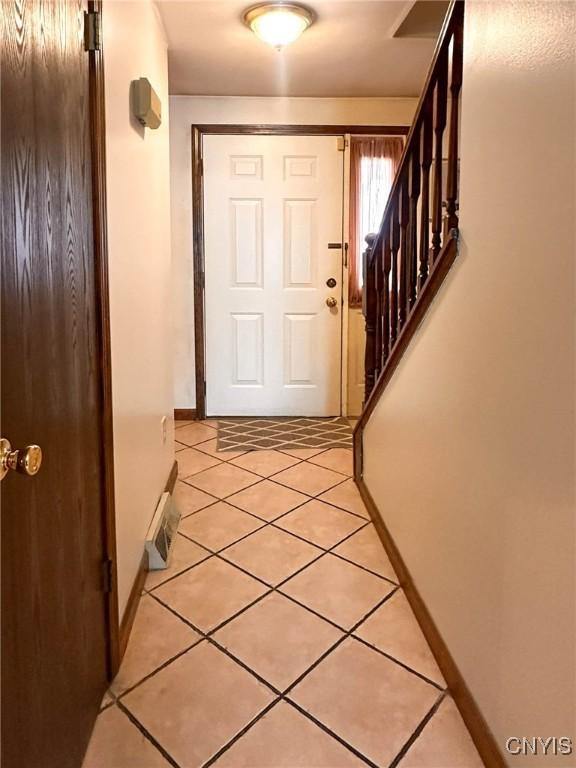 doorway featuring baseboards, stairs, and light tile patterned floors
