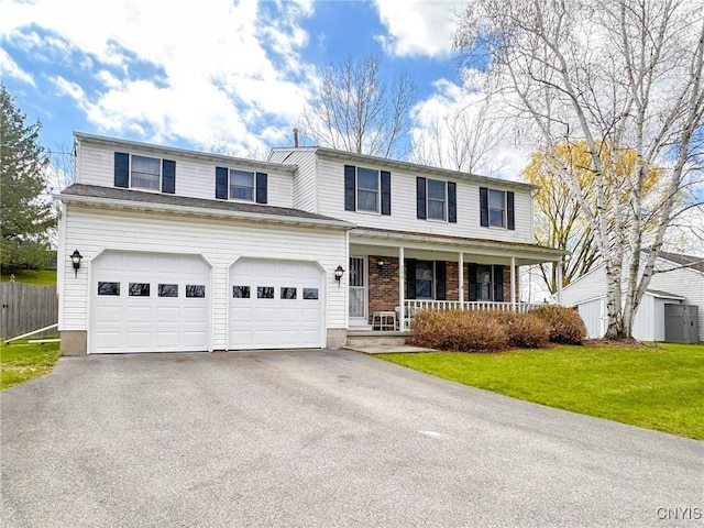 traditional-style home featuring fence, driveway, covered porch, a front yard, and a garage