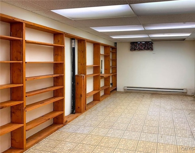 finished basement featuring a baseboard heating unit and a paneled ceiling
