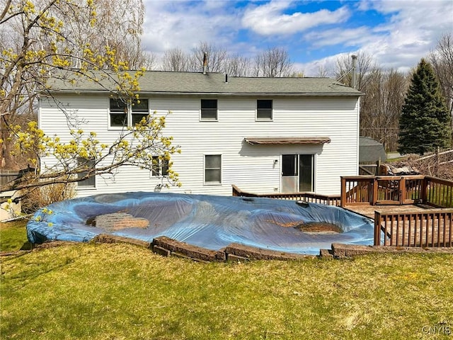 back of property featuring a lawn, a deck, and a shingled roof