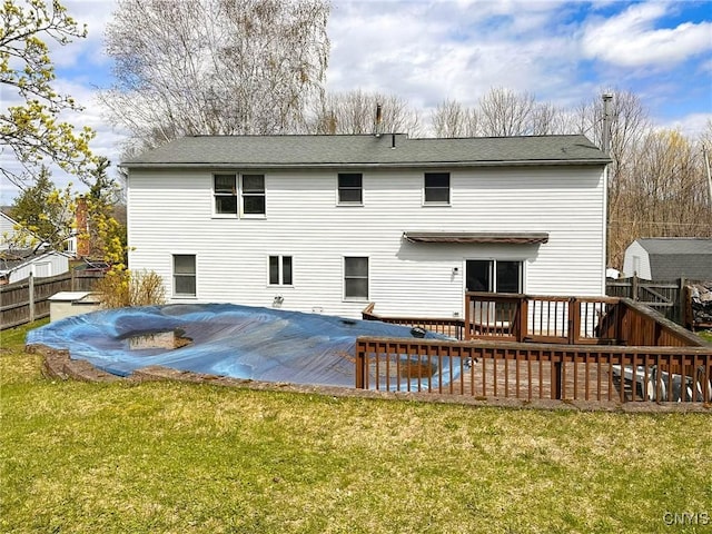 back of property featuring a lawn, a fenced backyard, a covered pool, and a deck