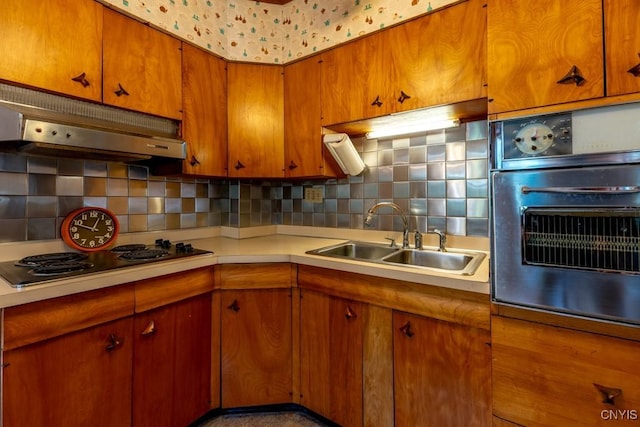 kitchen with oven, under cabinet range hood, light countertops, electric stovetop, and a sink
