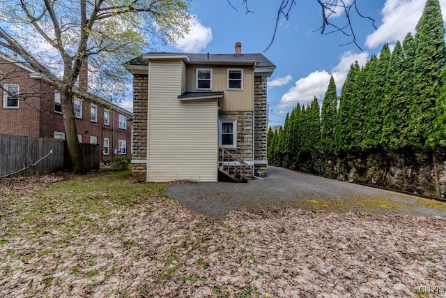 back of house featuring fence and stone siding