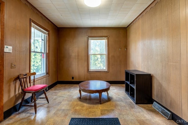 living area featuring wood walls, a healthy amount of sunlight, and visible vents