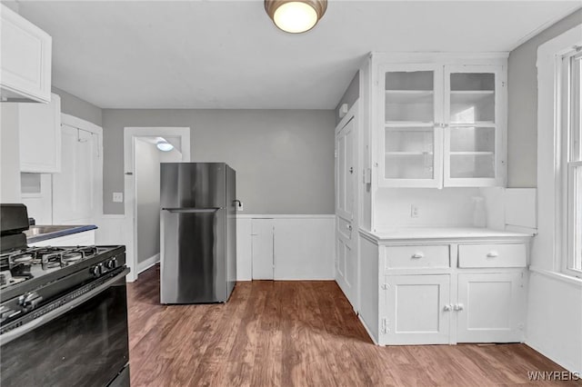 348 Virginia St, Buffalo, NY 14201 - kitchen featuring white cabinets, freestanding refrigerator, glass insert cabinets, black range with gas cooktop, and light countertops