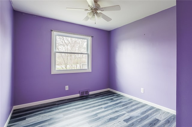 empty room with baseboards, wood finished floors, visible vents, and a ceiling fan