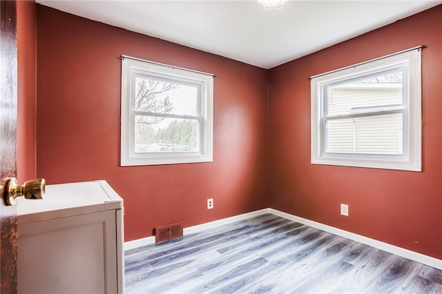 empty room featuring baseboards, visible vents, light wood-style floors, and a healthy amount of sunlight