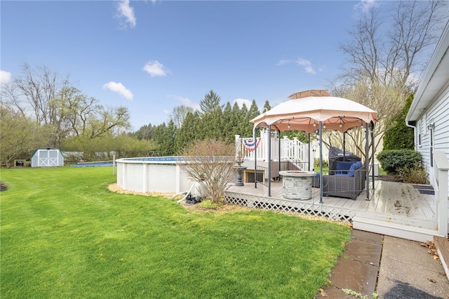 view of yard with an outdoor pool, a wooden deck, an outbuilding, a storage unit, and a gazebo