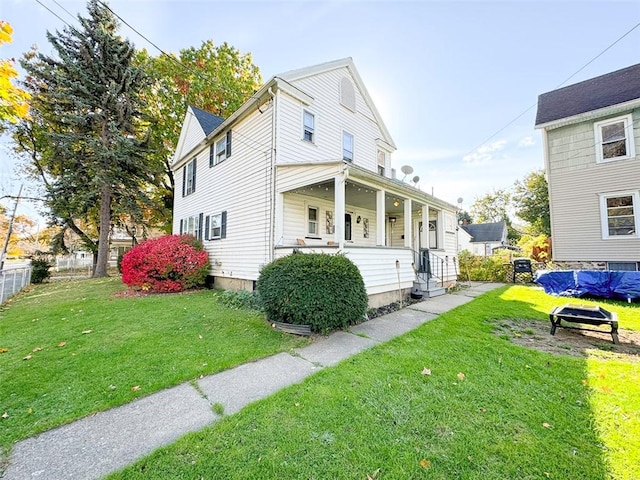 view of front facade featuring a porch, a front lawn, and fence
