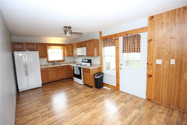 kitchen featuring light wood-style flooring, a sink, white appliances, and light countertops