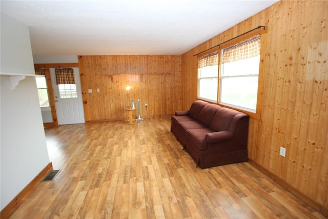 sitting room featuring light wood-type flooring, visible vents, wood walls, and baseboards
