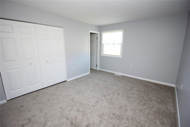 unfurnished bedroom featuring carpet floors, a closet, baseboards, and visible vents