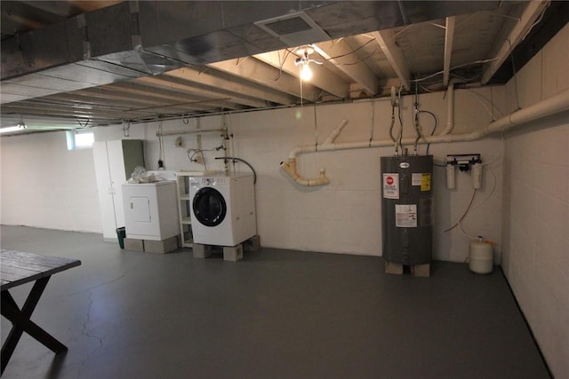 basement with water heater, concrete block wall, visible vents, and washer and dryer