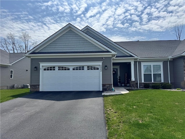 view of front of home featuring a garage, stone siding, a front yard, and aphalt driveway