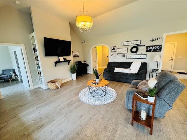 living area with high vaulted ceiling, wood finished floors, arched walkways, built in features, and baseboards