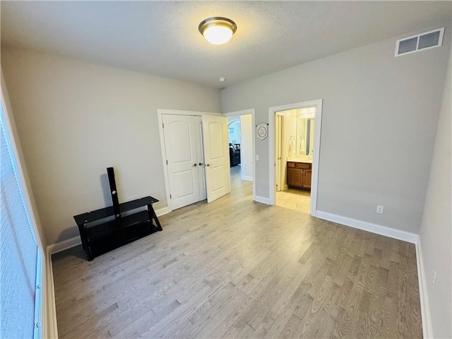 unfurnished bedroom with light wood-style floors, visible vents, and baseboards