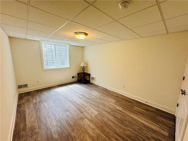 basement featuring baseboards, dark wood-style flooring, visible vents, and a paneled ceiling