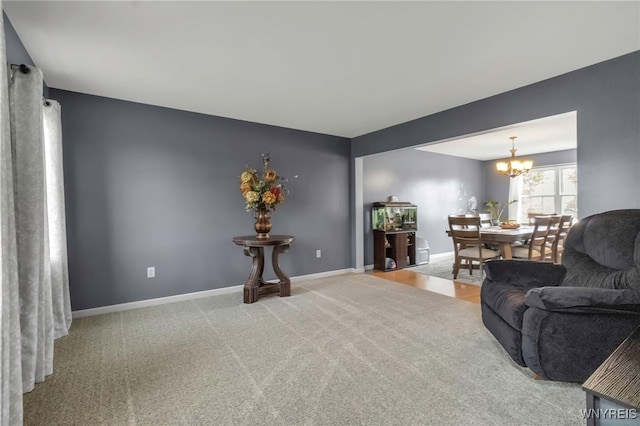 carpeted living area with a chandelier and baseboards