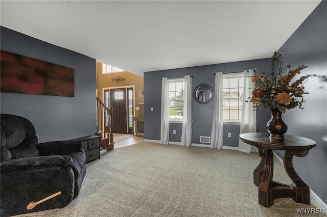 foyer entrance with stairway, baseboards, visible vents, and light colored carpet