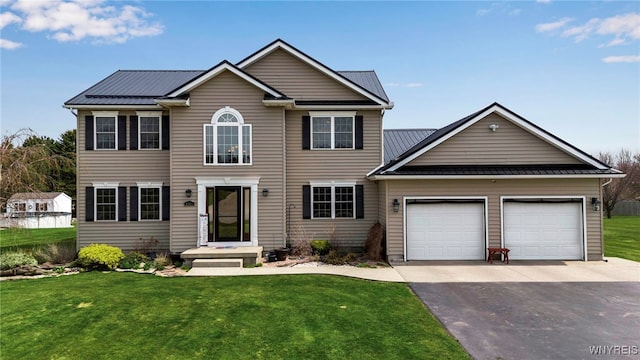 colonial home with a garage, metal roof, a front lawn, and aphalt driveway