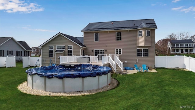 rear view of property featuring a lawn, a deck, a fenced in pool, and a fenced backyard