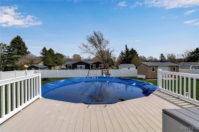 view of swimming pool featuring a fenced in pool, a fenced backyard, a shed, an outbuilding, and a deck