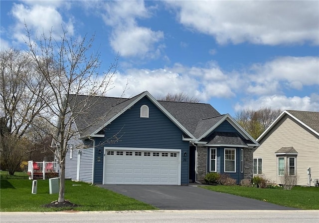 view of front facade with stone siding, an attached garage, a shingled roof, a front yard, and aphalt driveway