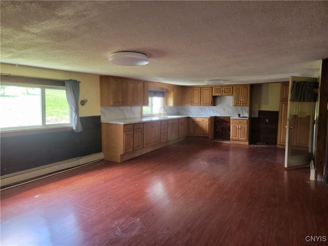 kitchen with a baseboard heating unit, dark wood-style floors, and a textured ceiling